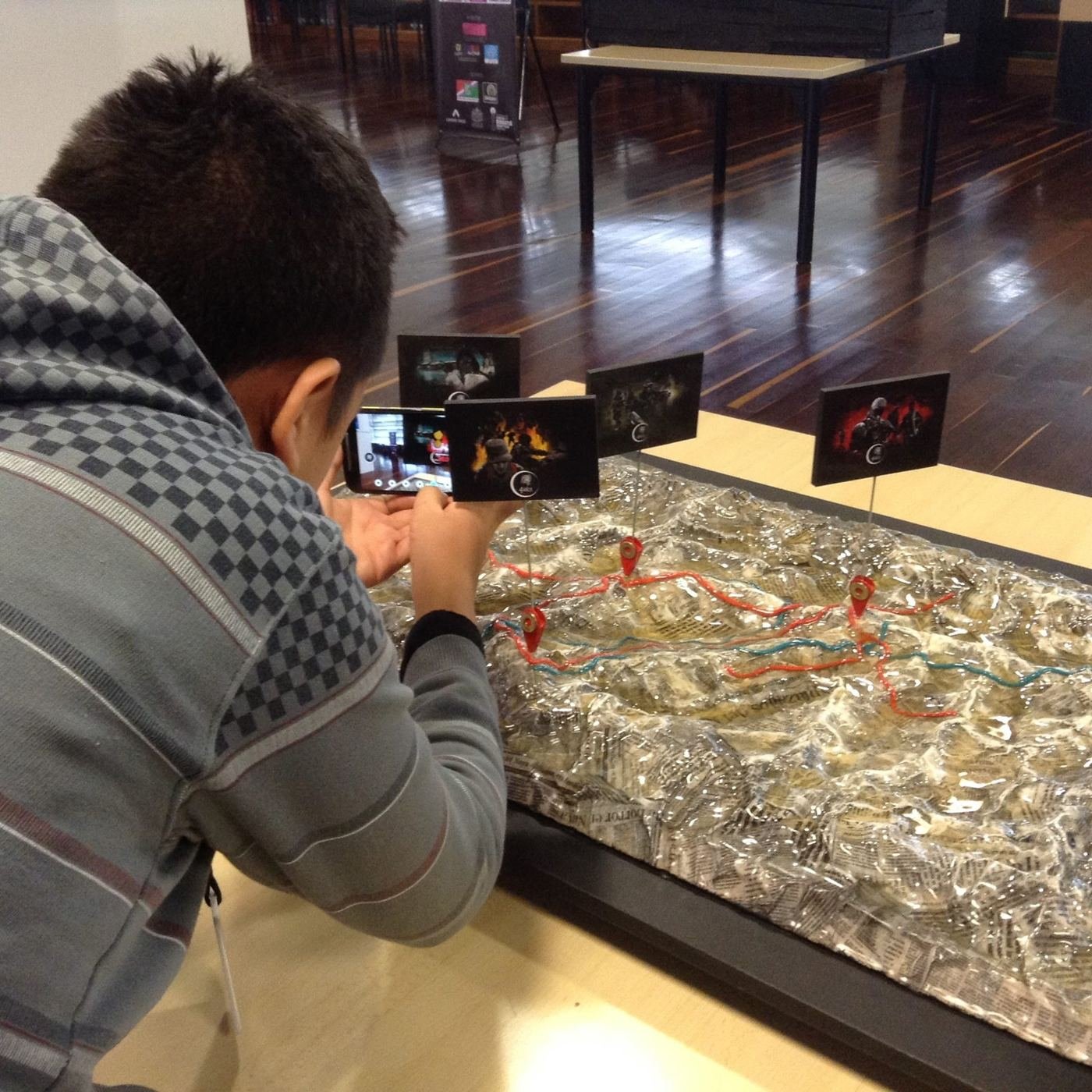 Un visitante apunta un celular a la maqueta