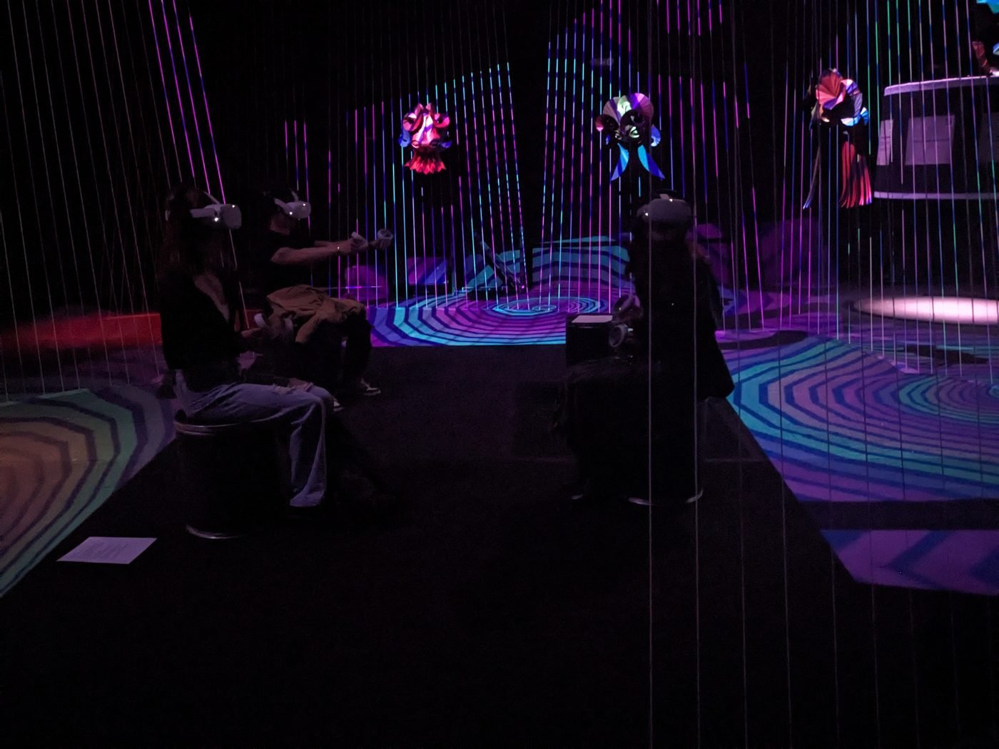 Sala de Códice Futuro: visitantes con visores de realidad virtual entre hilos y proyecciones