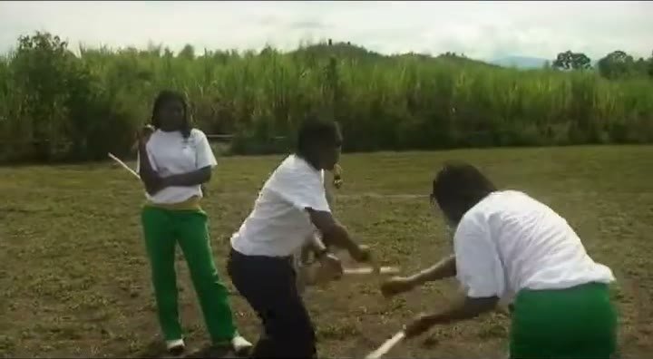 Jóvenes practican grima con palos en un potrero